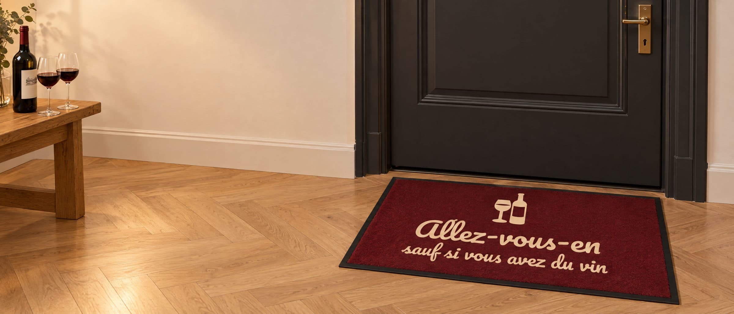 Tapis bordeaux « Allez-vous-en, sauf si vous avez du vin » devant une porte d’appartement