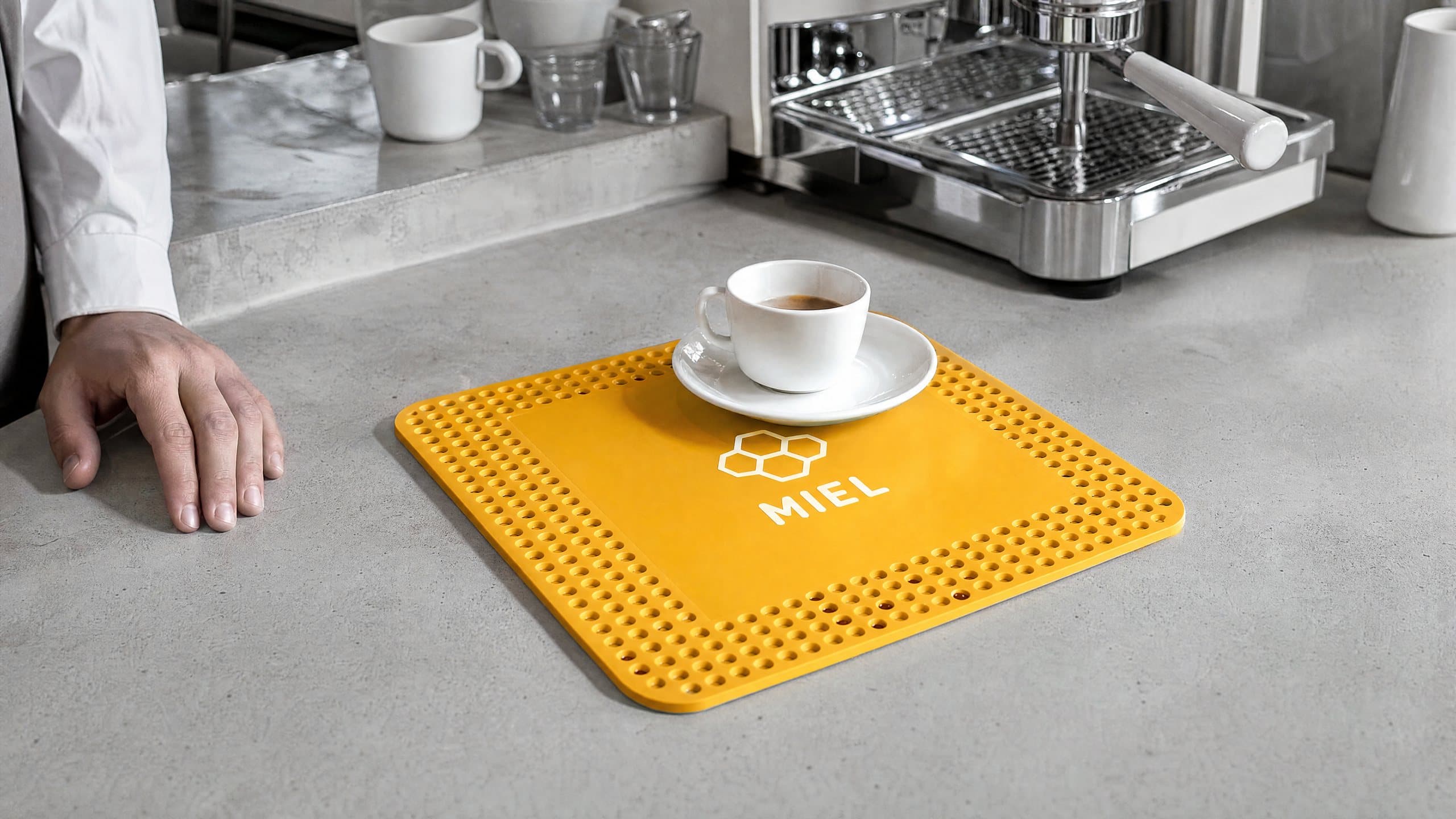 Tapis de comptoir jaune à alvéoles sous une tasse d’espresso, sur le comptoir d’un café