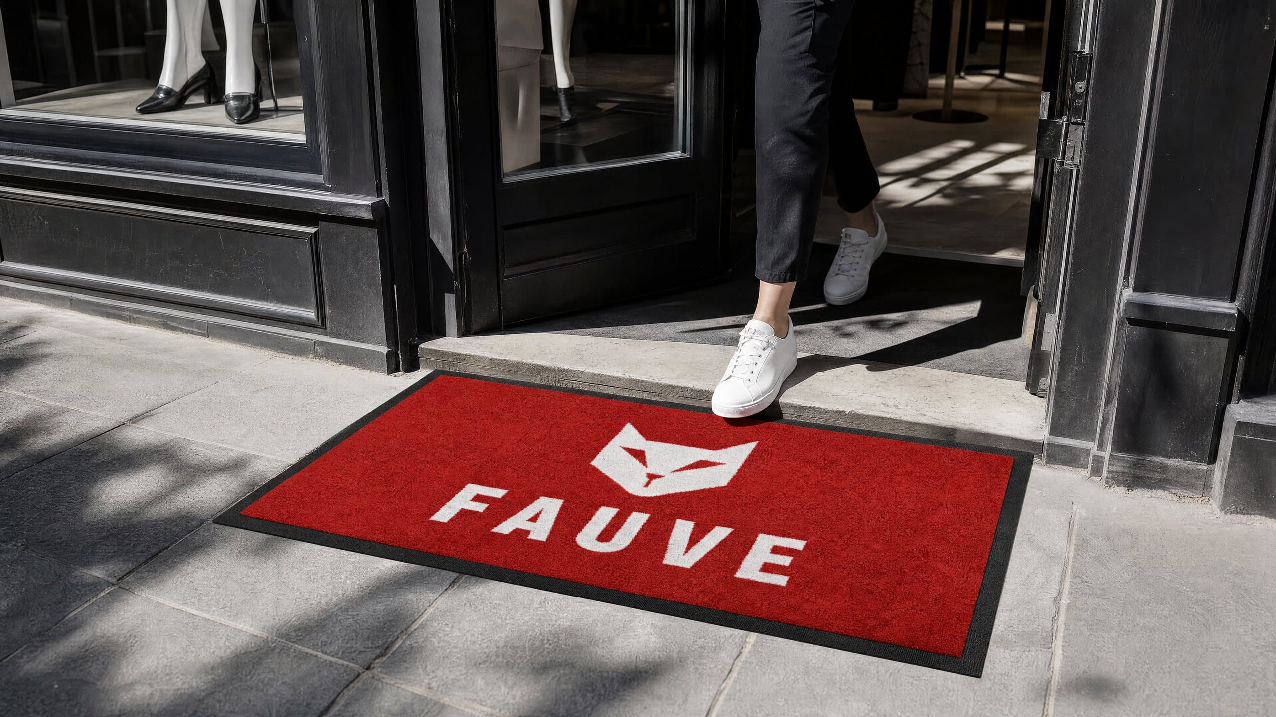 Tapis rouge au logo blanc devant une boutique de mode, une cliente entre
