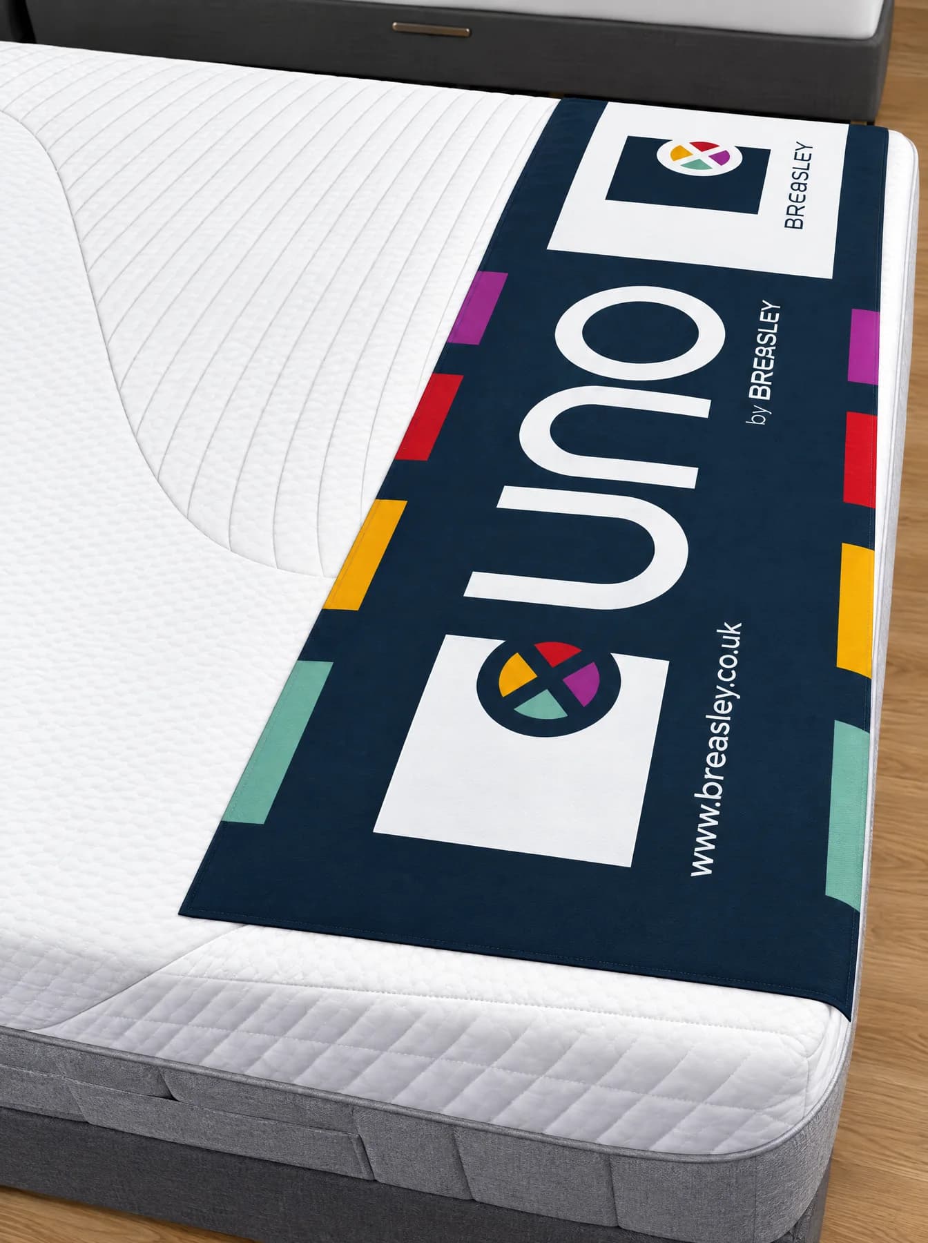 Illustration : Repose-pieds de lit bleu marine et multicolore sur un matelas de showroom