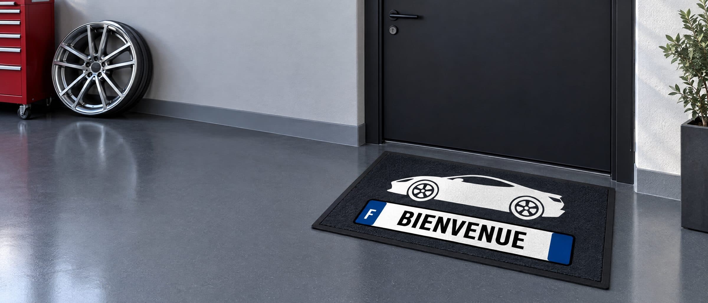Tapis anthracite avec une voiture de sport et une plaque d’immatriculation « BIENVENUE » devant la porte d’un garage
